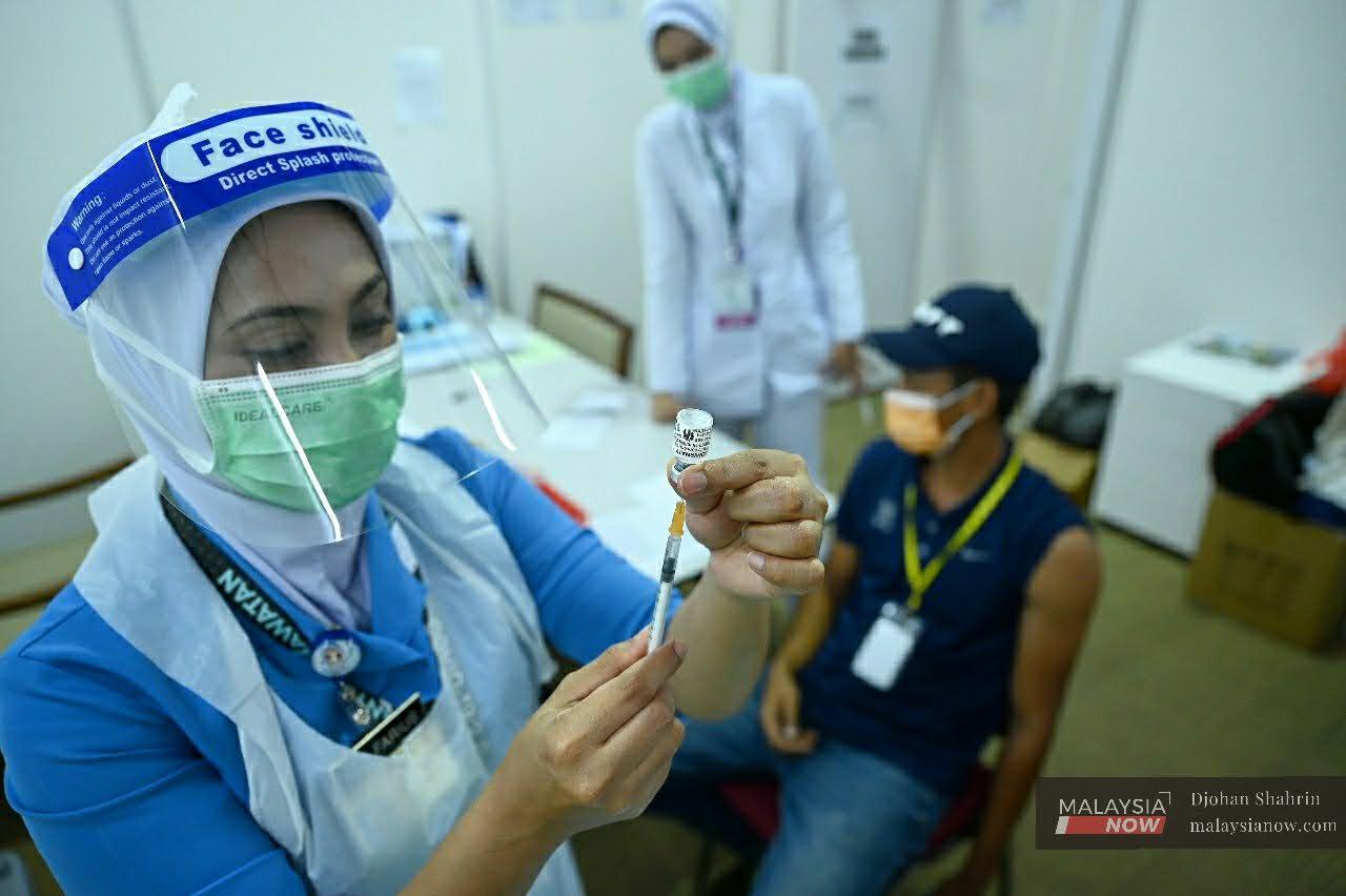 Petugas kesihatan menyiapkan suntikan vaksin kepada penerima di PPV Maeps, Serdang, Selangor.