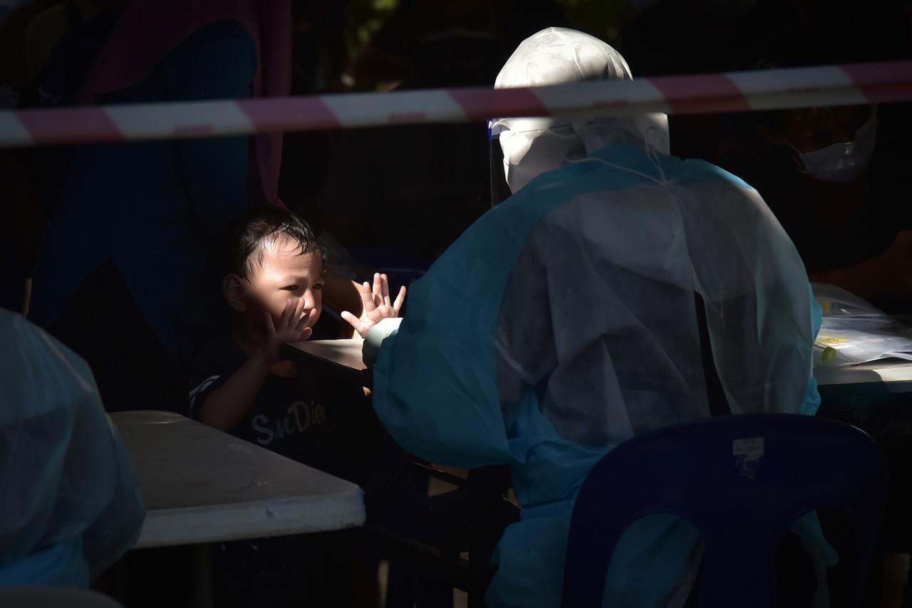 A health worker takes a swab sample from a child to be tested for Covid-19 at the Labuan Sports Complex today. Photo: Bernama
