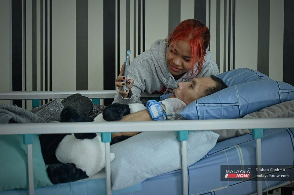 Nurul Syafiza Wan Shariman menunjukkan keputusan SPM kepada bapanya yang berbaring di atas katil akibat meningitis pada bulan Mei.