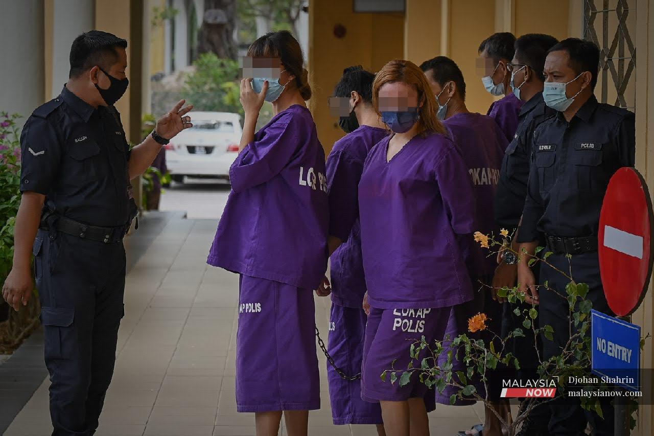 Police escort two Instagram users who were remanded for investigation into suspicions of inappropriate communication with minors, at the court in Bangi, Selangor, today.