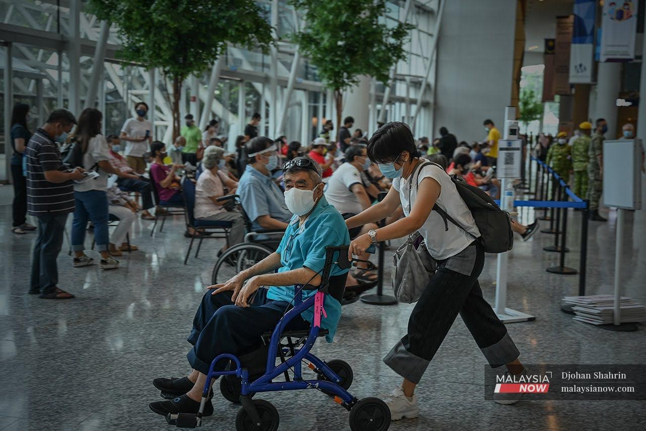 Seorang warga emas ditolak menggunakan kerusi roda oleh ahli keluarganya selepas menerima vaksin Sinovac di Malaysia International Trade and Exhibition Centre (Mitec), Jalan Dutamas.