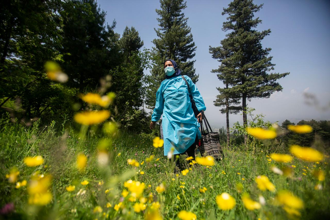 A health worker carrying vaccines walks up a hill during a vaccination drive against Covid-19 in Minnar village, north of Srinagar, Indian-controlled Kashmir, June 10. Photo: AP