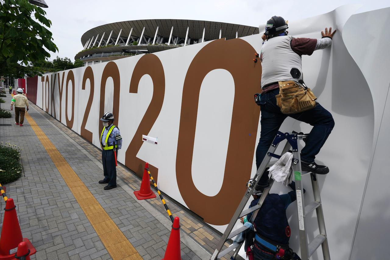 Workers paste an overlay on the wall of the National Stadium in Tokyo, where the opening ceremony and many other events are scheduled for the postponed 2020 Olympics, June 2. Photo: AP