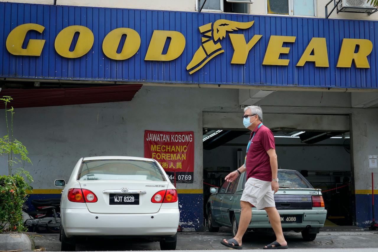 A man wearing a face mask walks past a Goodyear shop in Bukit Jalil today. The industrial tribunal has ruled in favour of 65 migrant workers who sued the US tyre-maker for underpaying them, their lawyer says, calling it a victory for foreign employees. Photo: AP