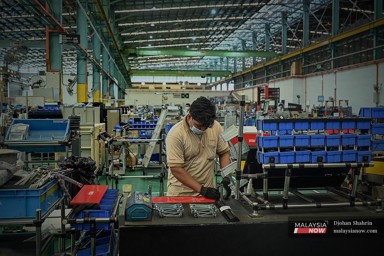 A worker adjusts equipment at an electrical and electronics factory in Kota Damansara, Selangor.