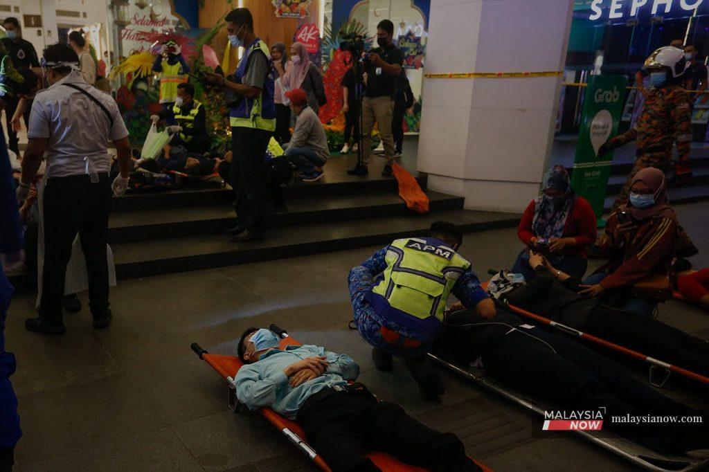Passengers lie on stretchers on the ground after being helped out of the LRT train by personnel from the fire and rescue department after the collision on May 24.