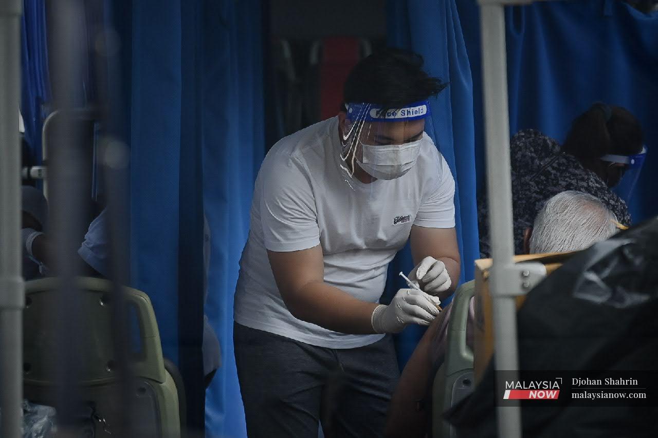 Petugas kesihatan memberi suntikan vaksin kepada warga emas didalam bas bergerak di Pangsapuri PKNS, Kampung Baru.Mobiliti vaksinasi Covid-19 menjadi salah satu usaha 'outreach' orang ramai untuk meningkatkan kadar vaksinasi.