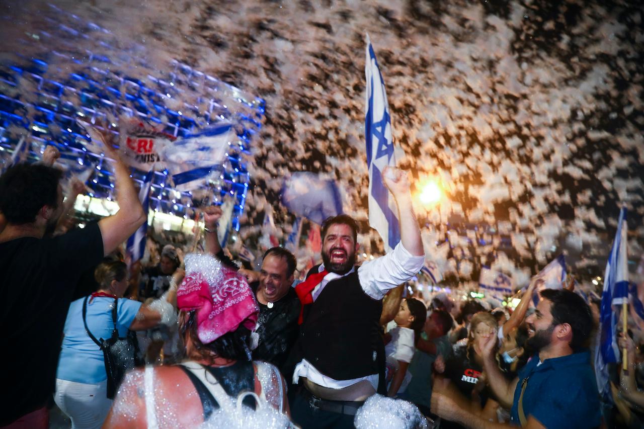 Israelis celebrate the swearing in of the new government in Tel Aviv, Israel, June 13. Israel's parliament has voted in favour of a new coalition government, formally ending Prime Minister Benjamin Netanyahu's historic 12-year rule. Naftali Bennett, a former ally of Netanyahu became the new prime minister. Photo: AP