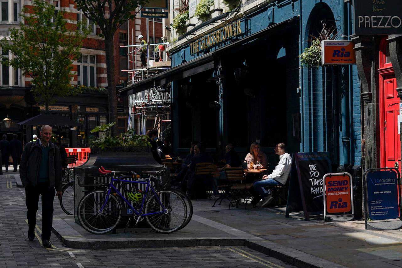 People sit at tables outside a pub in Soho, as pubs, cafes and restaurants in England reopen indoors under the latest easing of the coronavirus lockdown in London, May 18. Stage four of the government's roadmap out of lockdown would have seen all legal limits on social contact removed. Photo: AP
