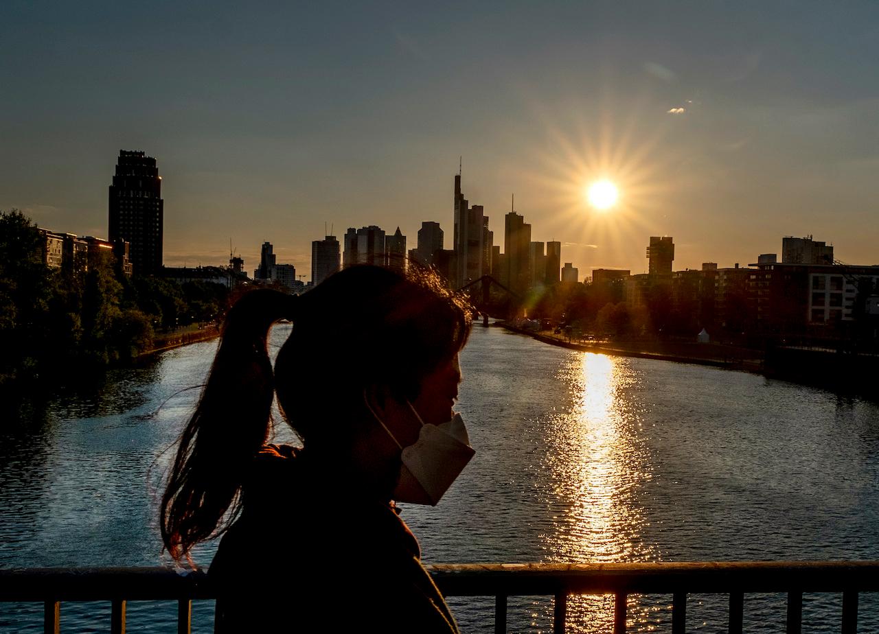 A woman wearing a face mask walks across a bridge over the river Main in Frankfurt, Germany, May 7. Photo: AP