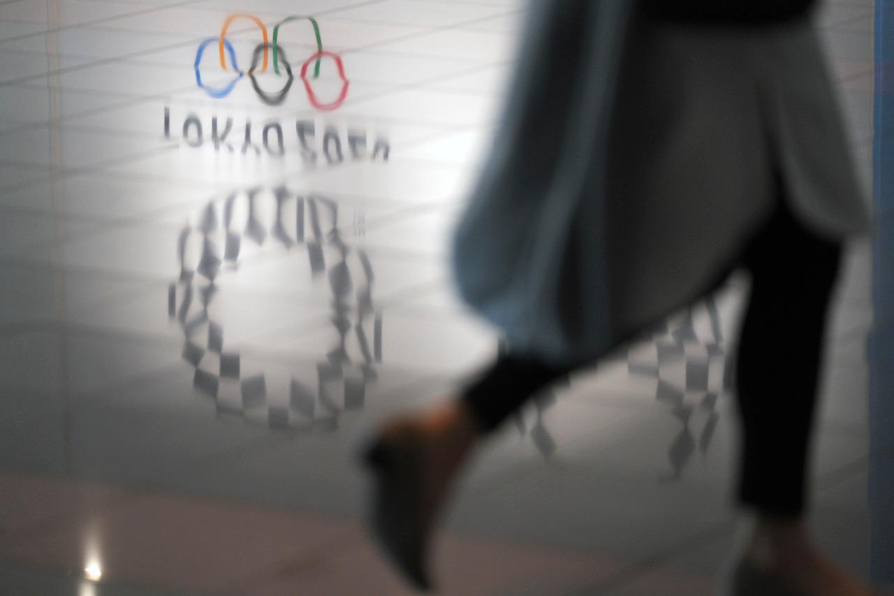A woman walks near a reflection of Tokyo 2020 logo on the floor in Haneda Airport in Tokyo, June 14. Photo: AP