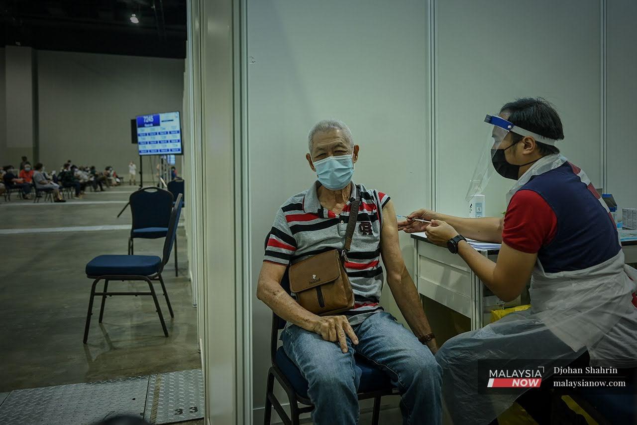 A health worker administers a dose of Sinovac Covid-19 vaccine to a senior citizen at the Mitec vaccination centre in Kuala Lumpur.
