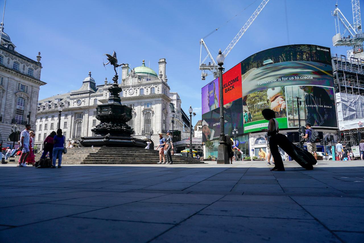 People walk in Piccadilly Circus, in London, June 14 when government announced it was delaying steps to lift restrictions due to concern over the spread of the Delta strain, first detected in India. Photo: AP