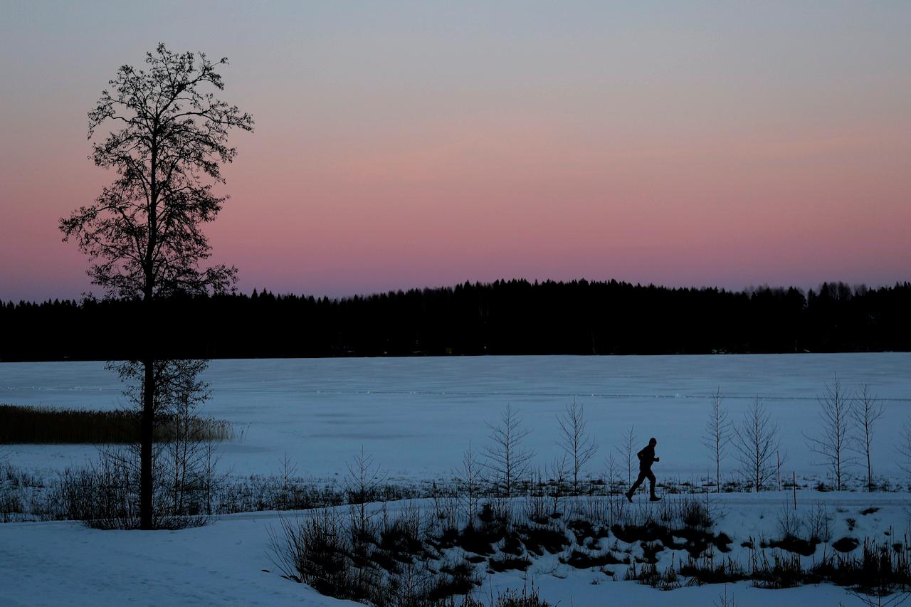 A man jogs at the frozen lake Iso-Kukkanen during sun down near Lahti, Finland, Feb 21, 2017. Photo: AP