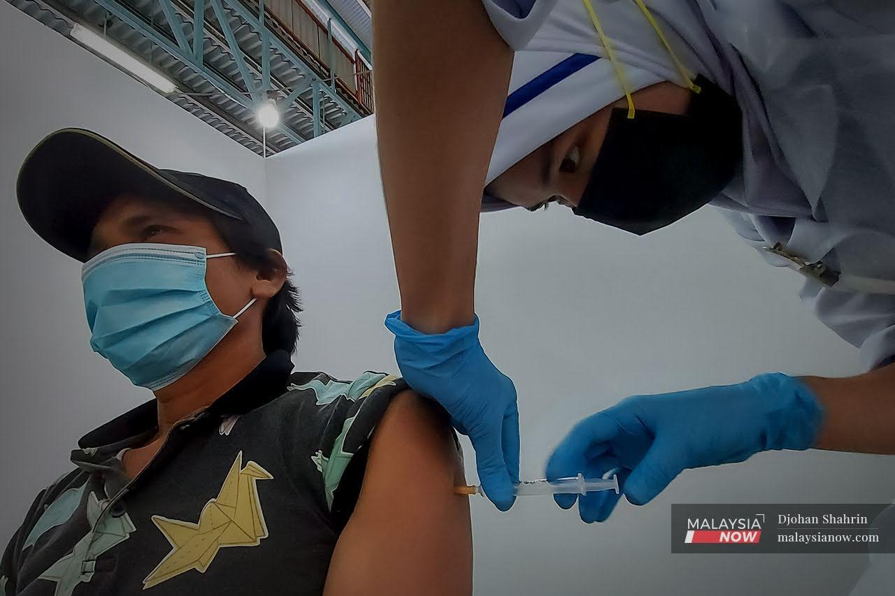 Petugas kesihatan dari Pusat Kesihatan Tangling memberikan suntikan vaksin dos ke dua  kepada penghuni Pusat Transit Gelendangan Kuala Lumpur di Anjung Kelana, Taman Desa.