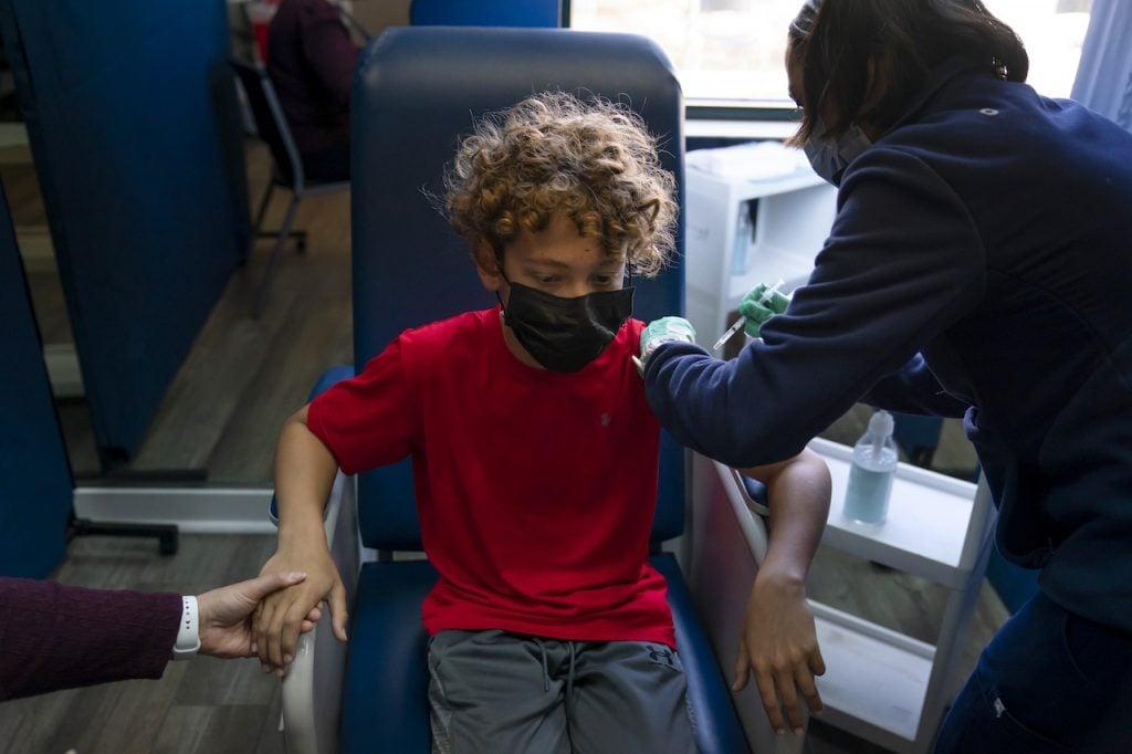A 12-year-old in Tustin, California, holds his mother's hand as he receives the Pfizer Covid-19 vaccine from a health worker on May 13. Photo: AP