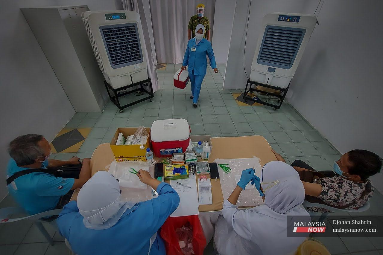 Petugas kesihatan dari Pusat Kesihatan Tangling membawa penambahan stok vaksin ke PPV Anjung Kelana, Taman Desa.