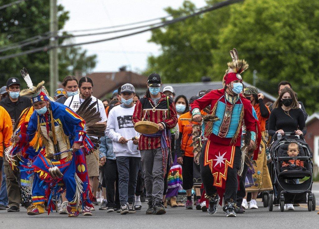 Members of the community of the Kahnawake Mohawk Territory in Quebec march through the town on May 30, to commemorate the news that a mass grave of 215 indigenous children were found at the Kamloops Residential School in British Columbia, Canada. Photo: AFP