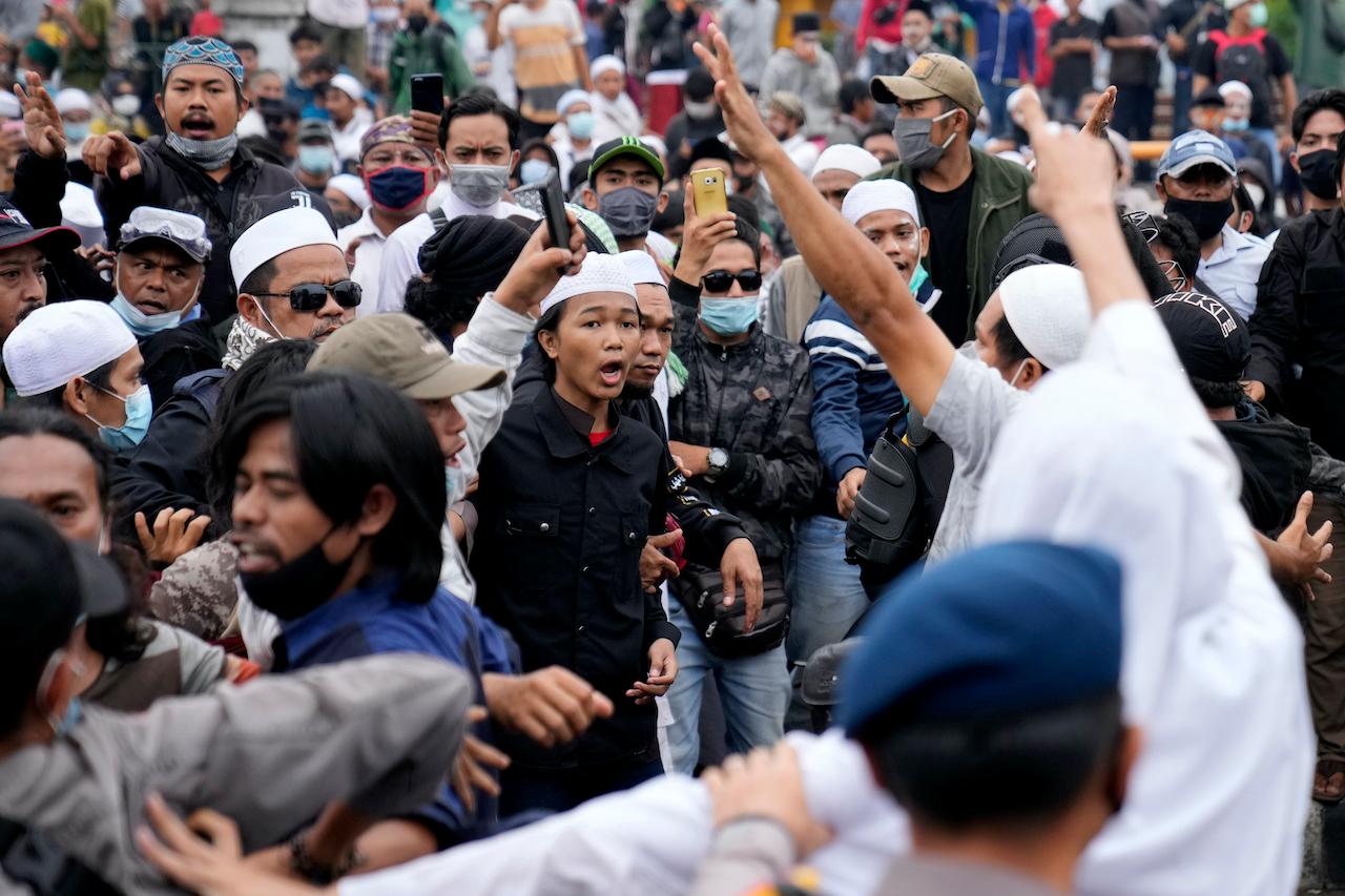 Supporters of firebrand cleric Rizieq Shihab shout slogans during a rally near the district court where his sentencing hearing was held in Jakarta, Indonesia, June 24. The influential cleric was sentenced to another four years in prison for concealing information about his coronavirus test result. Photo: AP