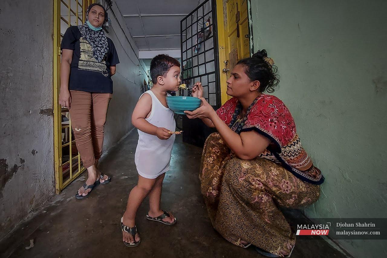 Pelarian Myanmar Islam, menyuap makanan kepada anaknya di koridor kediamannya, mereka menghabiskan masa berbual dengan jiran tetangga disepanjang perintah kawalan pergerakan (PKP) dilanjutkan sehingga 28 Jun 2021 di Selayang.