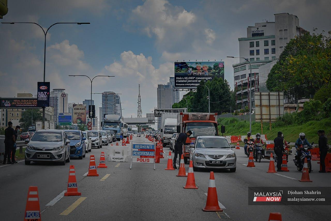 Police officers check vehicles at a roadblock along the Federal Highway in Kuala Lumpur.
