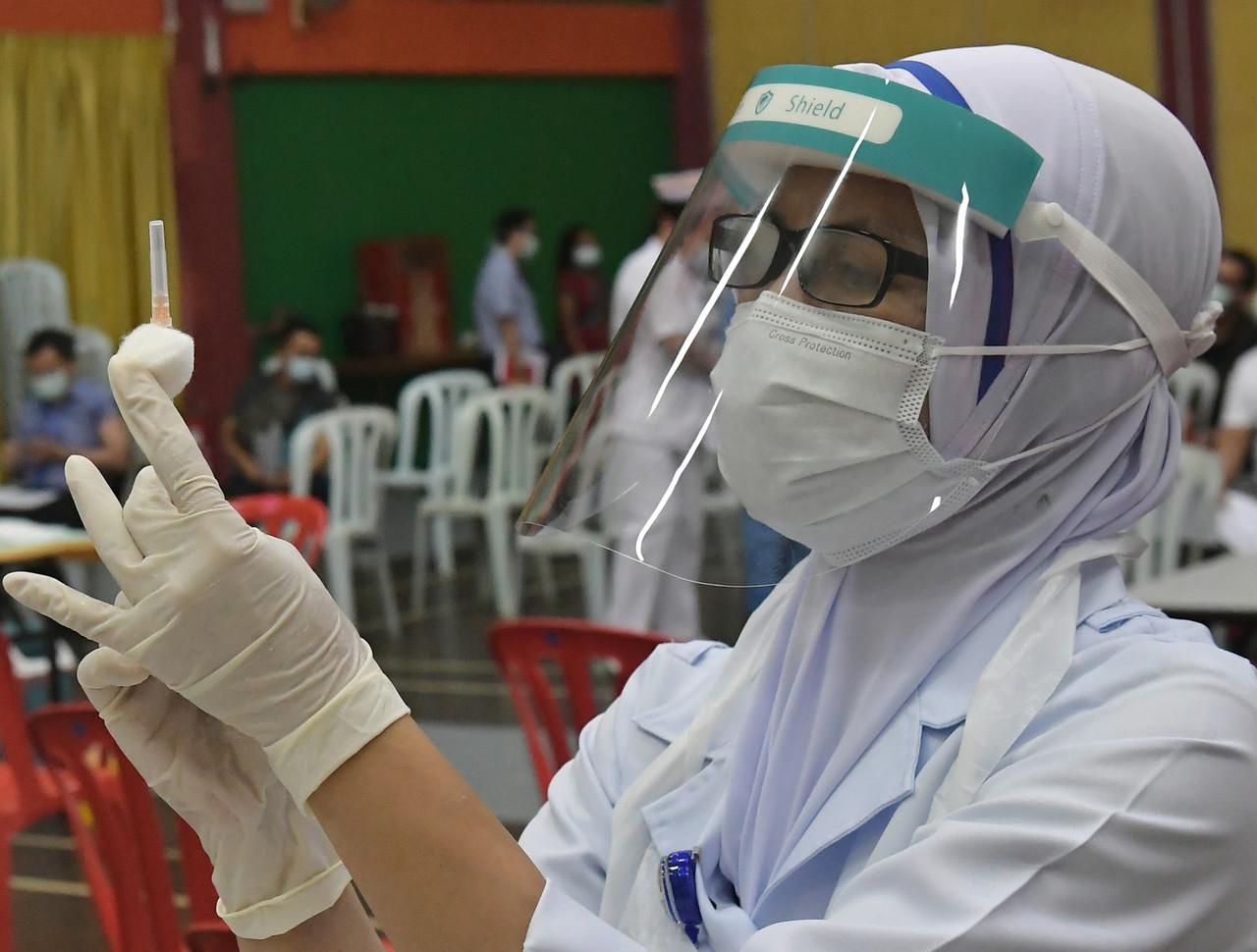 A nurse prepares a syringe of Covid-19 vaccine at the Stadium Perpaduan vaccination centre in Kuching. Photo: Bernama