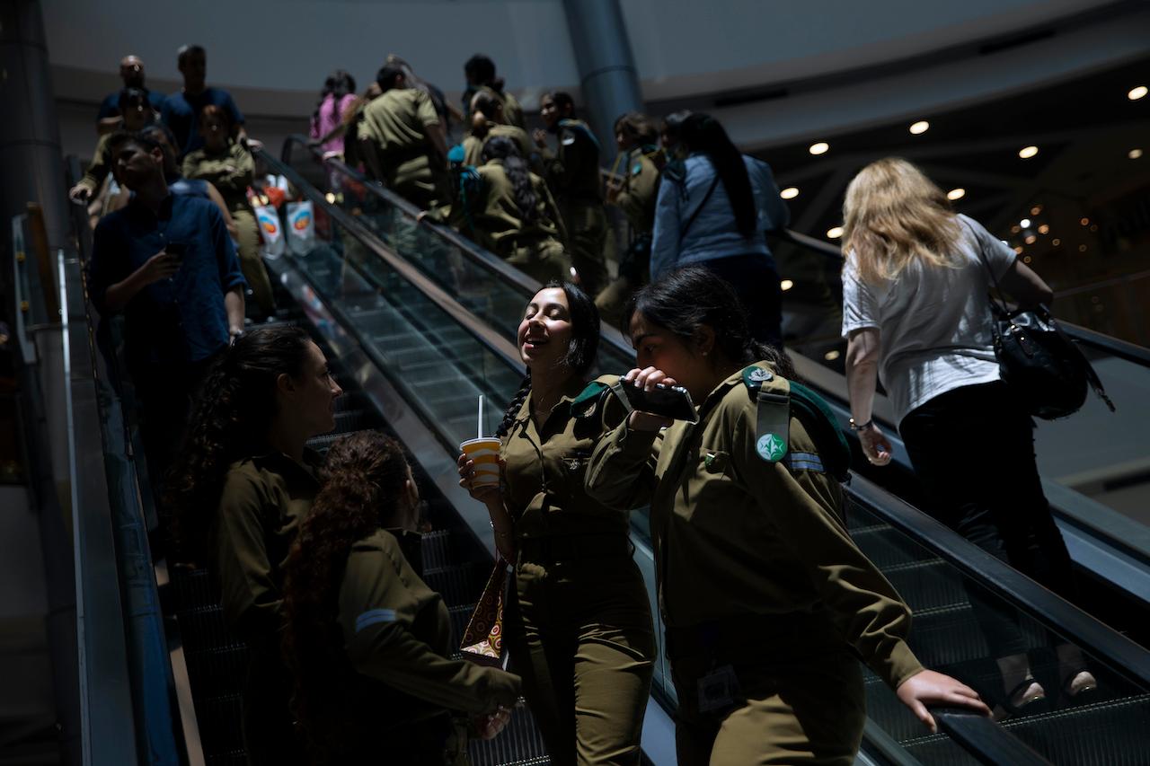 People ride an escalator at a shopping mall after restrictions requiring face masks indoors was lifted, in Tel Aviv, June 15. Photo: AP