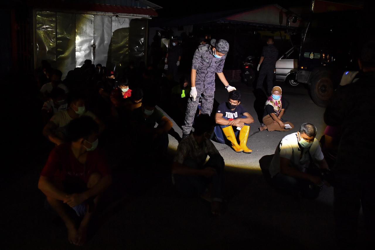 An officer from the immigration department checks a foreigner arrested during an operation at the Selangor wholesale market early this morning. Photo: Bernama