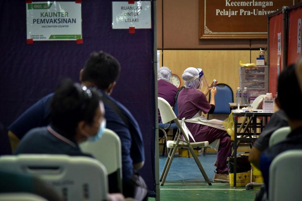 Penduduk kampung menunggu giliran vaksinasi di PPV Dewan Mutiara Matrikulasi Labuan. Gambar: Bernama