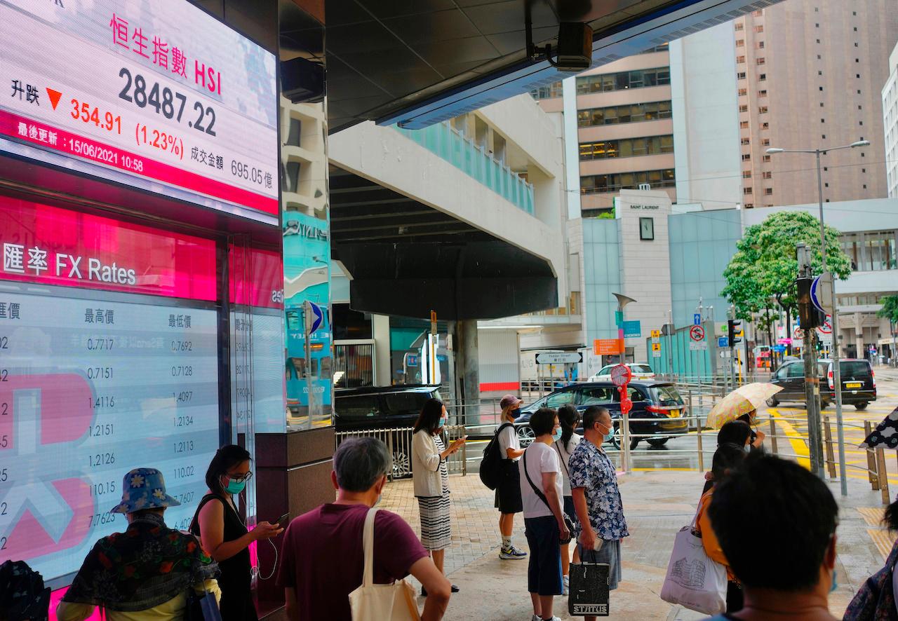People walk past a bank's electronic board showing the Hong Kong share index at the Hong Kong Stock Exchange in Hong Kong, June 15. Photo: AP