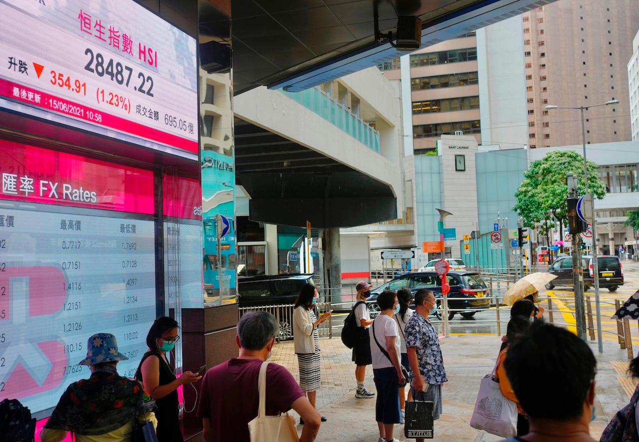 People walk past a bank's electronic board showing the Hong Kong share index at the Hong Kong Stock Exchange in Hong Kong, June 15. Photo: AP