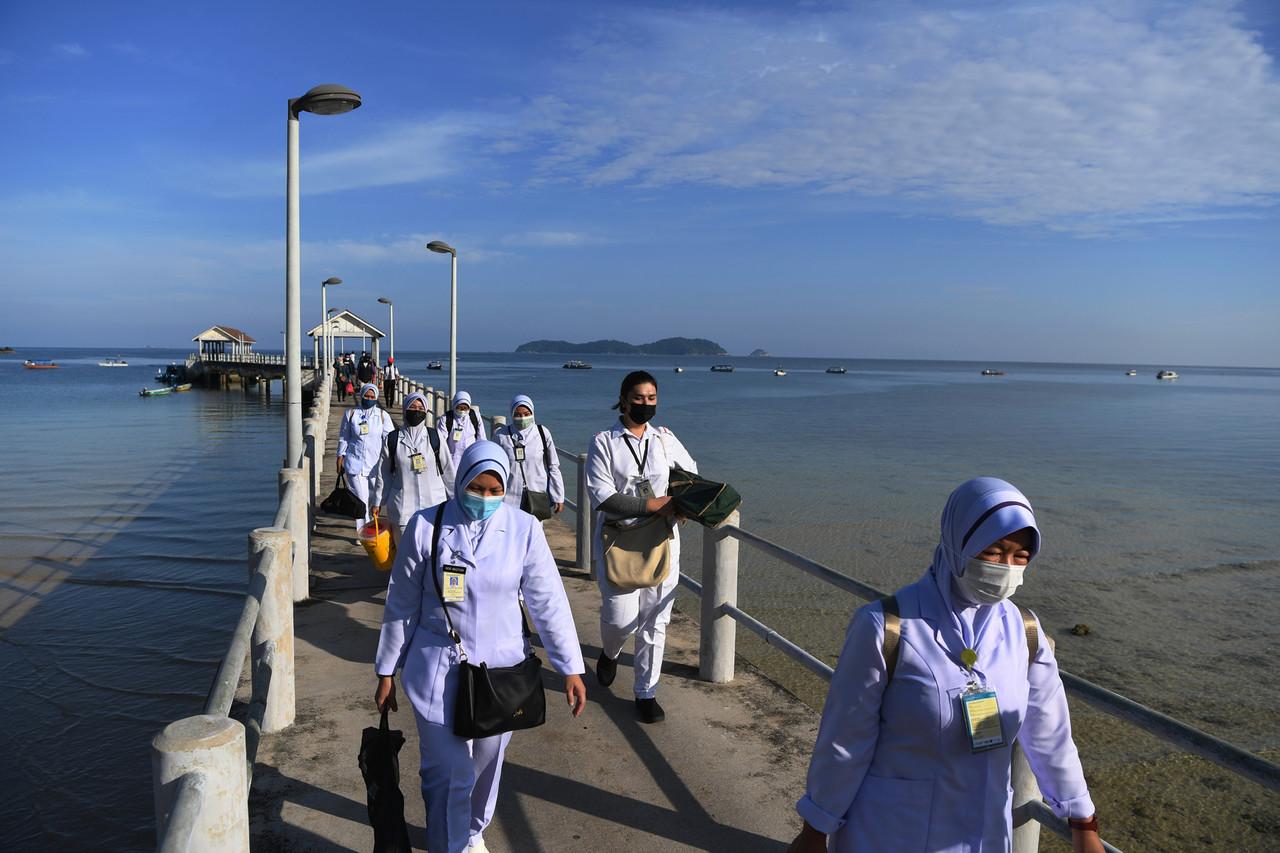 Frontline workers carrying vaccination supplies board a boat to Tioman island in order to carry out the national immunisation programme at Kampung Salang there. Photo: Bernama