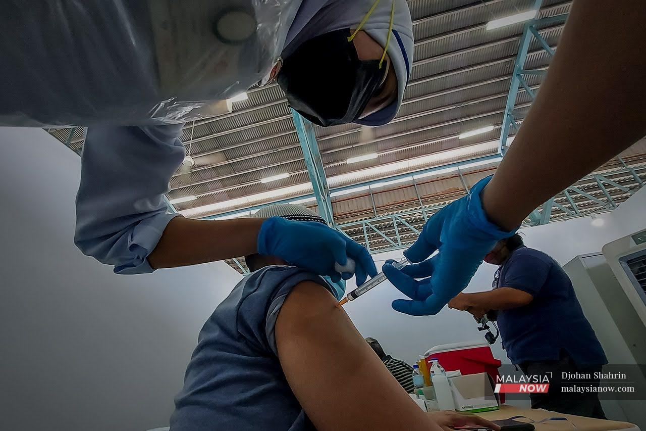 Petugas kesihatan dari Pusat Kesihatan Tangling memberikan suntikan vaksin dos ke dua kepada penghuni Pusat Transit Gelendangan Kuala Lumpur di Anjung Kelana, Taman Desa.