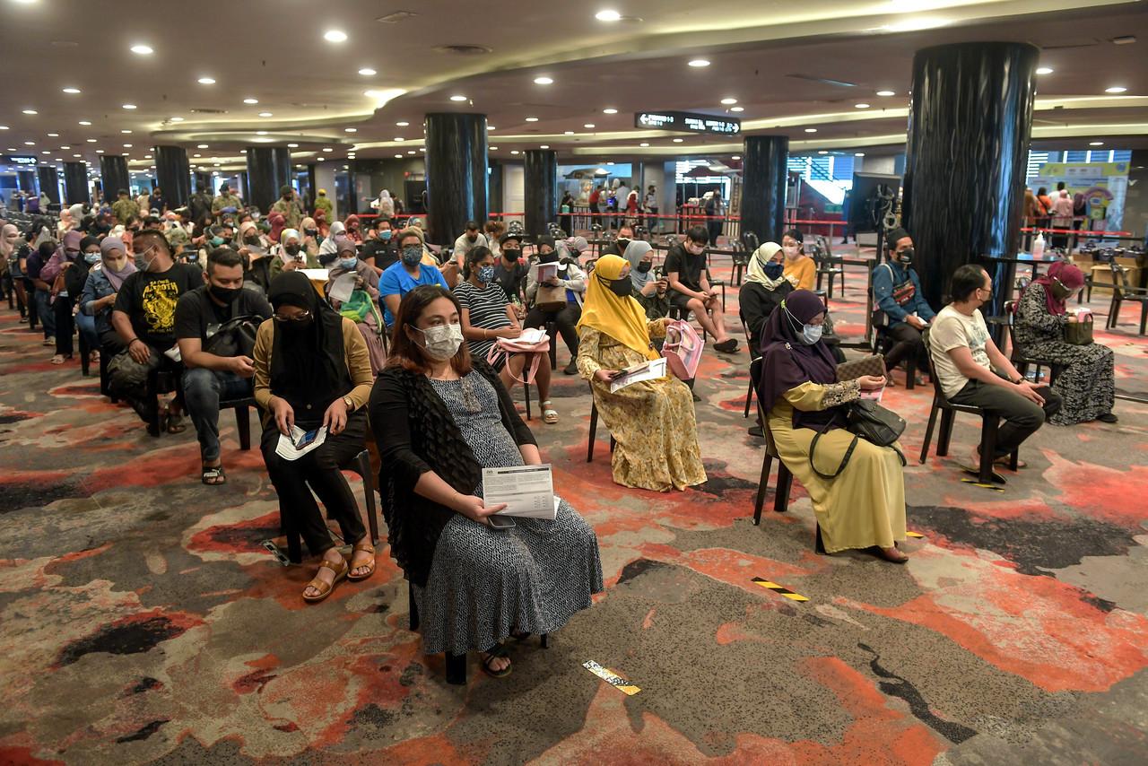 A pregnant woman waits alongside others to receive a Covid-19 jab at the Sunway Pyramid Convention Centre. Photo: Bernama