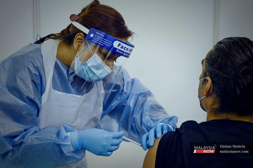 A health worker administers a dose of AstraZeneca vaccine at the World Trade Centre vaccination centre in Kuala Lumpur.
