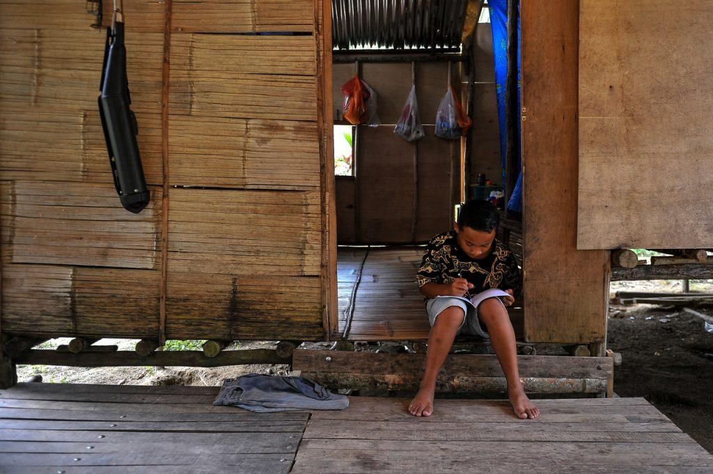 An Orang Asli student in Standard Six does his lessons at his home in Hulu Langat, Selangor, during the second round of movement control order in January this year. Many rural households have limited access to the technology needed to move their lives online. Photo: Bernama