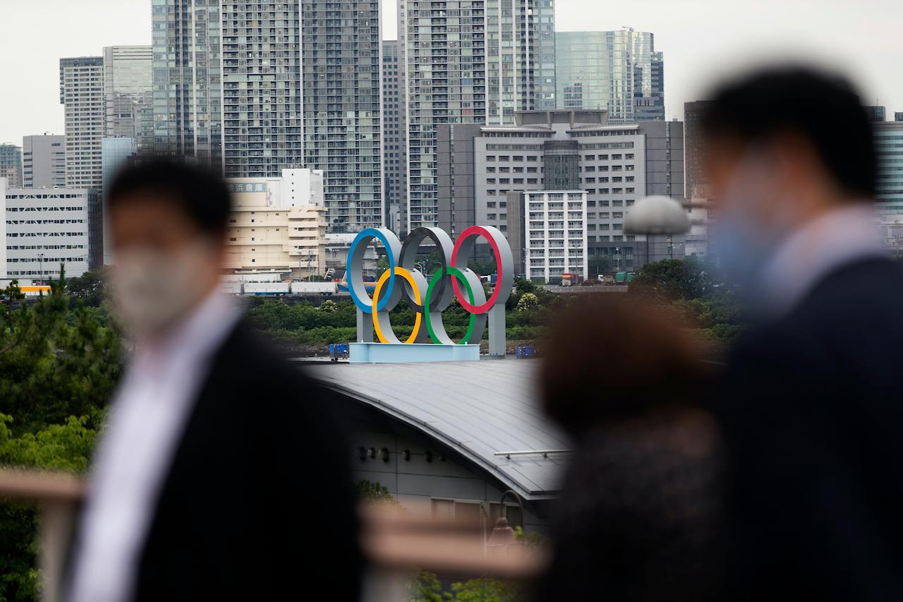 The statue of the Olympics rings overlooks people visiting a nearby shopping mall in Tokyo, July 1. Covid-19 cases have been rising in Japan since a state of emergency was lifted last month and replaced with softer restrictions that are set to expire on July 11. Photo: AP