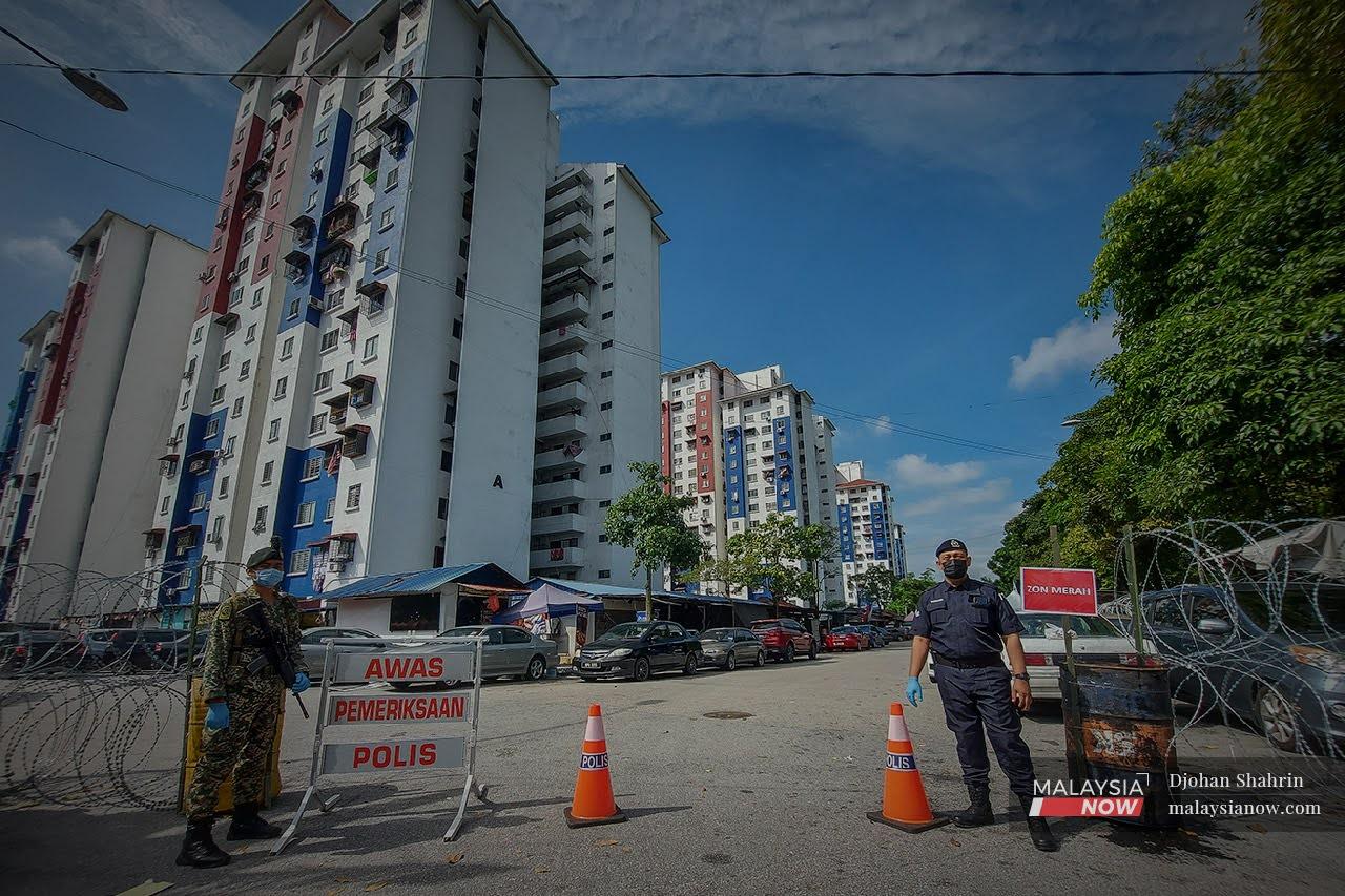 Police and army personnel monitor the entrance to the Pantai Ria flats in Pantai Dalam, Kuala Lumpur, which have been placed under enhanced movement control order until July 14.