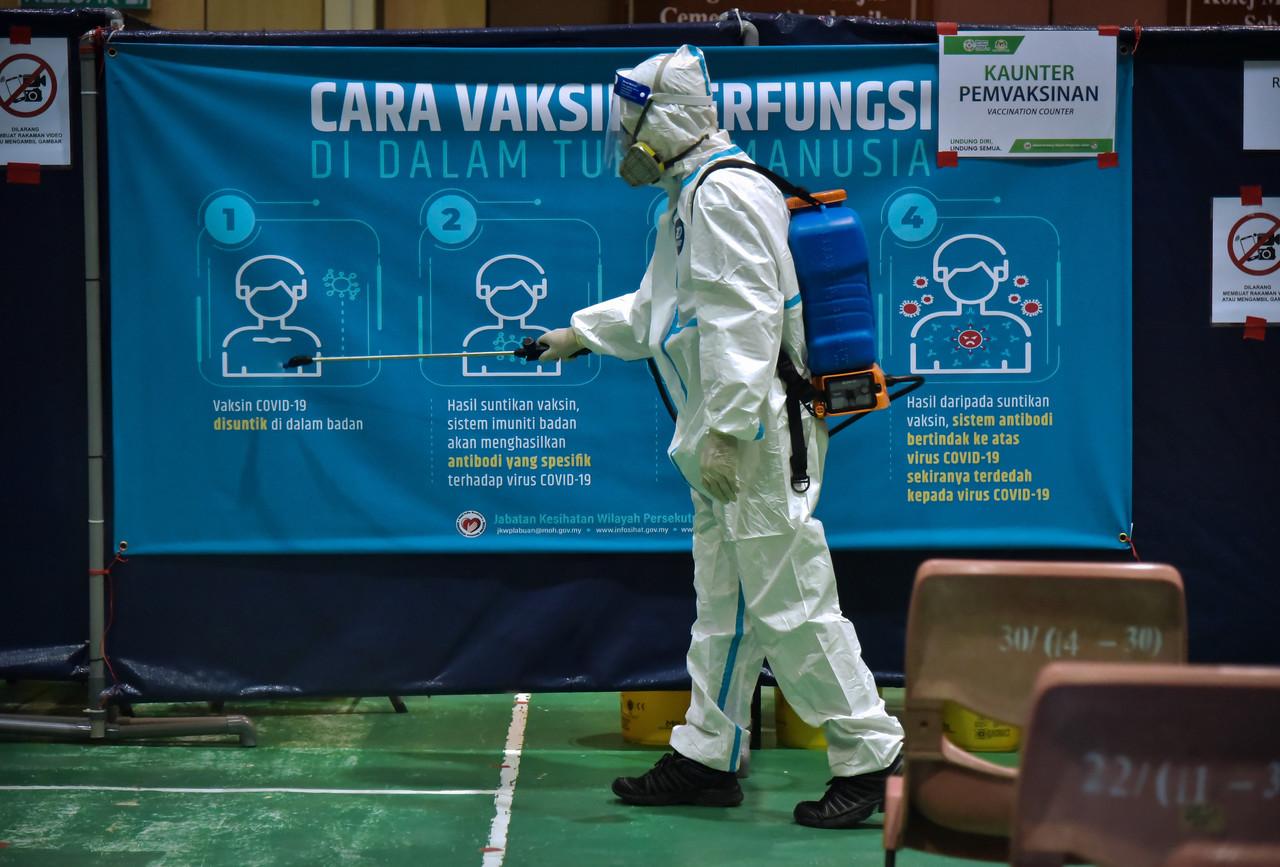 A health worker sprays sanitiser at a vaccination centre in Labuan. Photo: Bernama