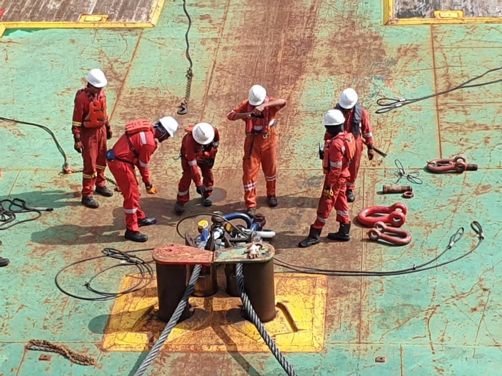 A team of workers performs a check of some machinery on the platform of their oil rig.