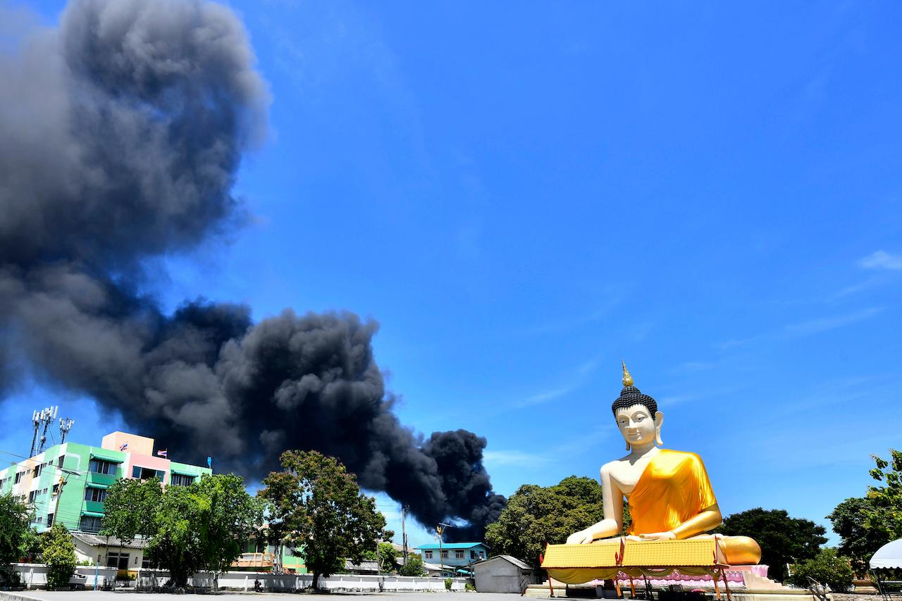 Smoke rises behind the giant Buddha statue in Samut Prakan province, Thailand, July 5. A massive explosion at a factory on the outskirts of Bangkok early today shook an airport terminal serving Thailand's capital and prompted the evacuation of residents from the area. Photo: AP