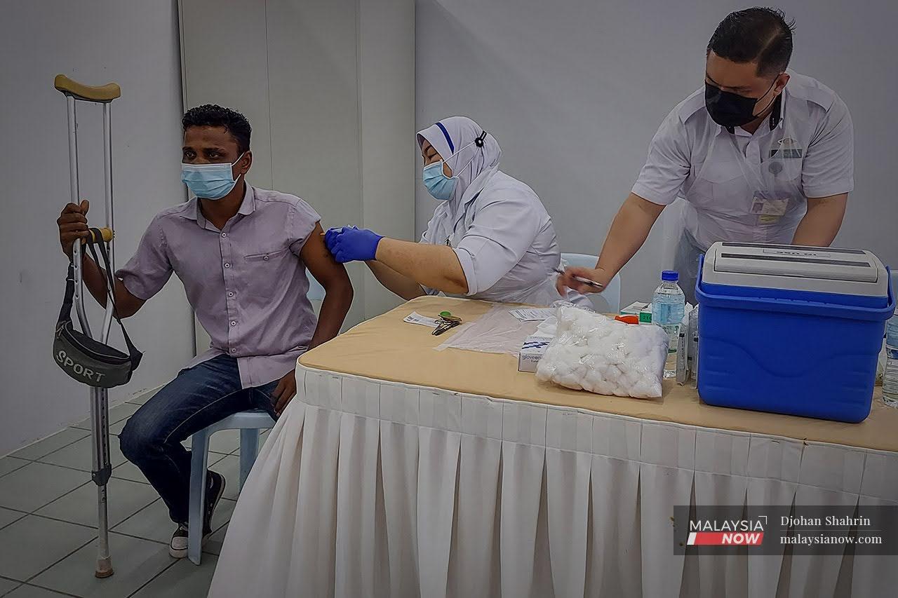 Petugas kesihatan dari Pusat Kesihatan Tangling memberikan suntikan vaksin dos ke dua kepada penghuni yang menghuni di Pusat Transformasi Gelendangan Anjung Kelana, Taman Desa.