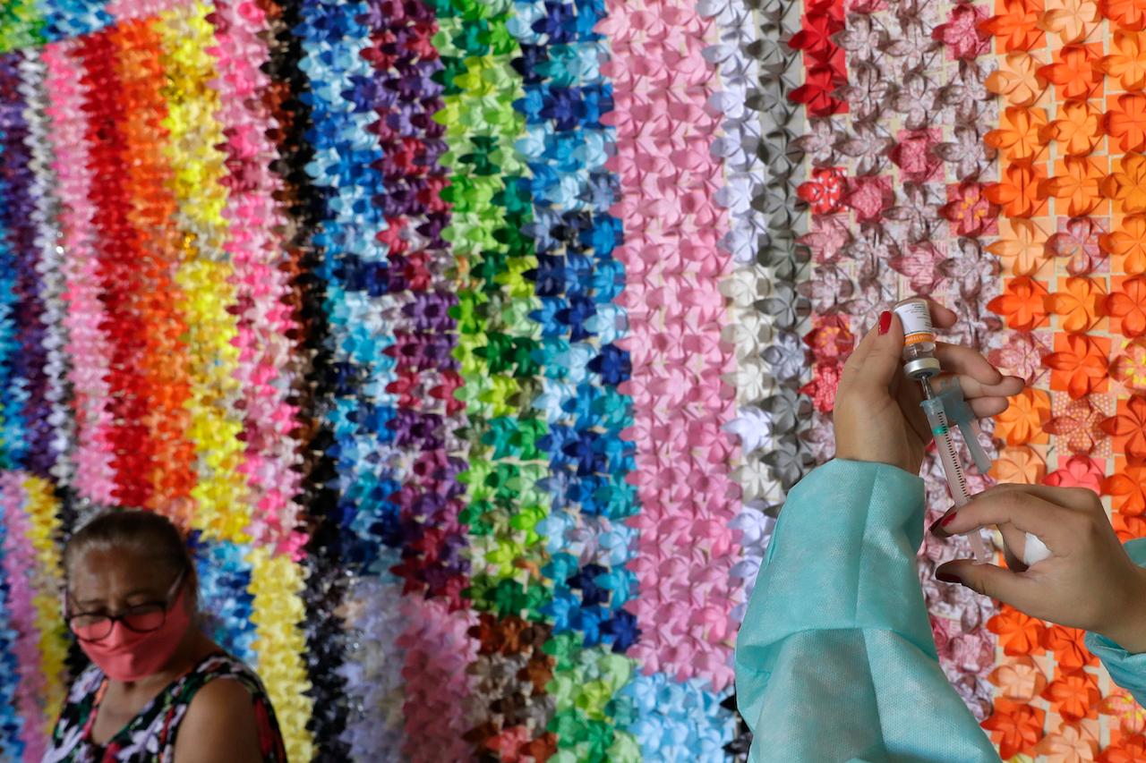 A health worker prepares a shot of the Sinovac vaccine for Covid-19 in front of a panel of origami lotus flowers, placed in honour of victims of the pandemic, at a health centre in Brasilia, Brazil, in this March 29 file photo. Photo: AP