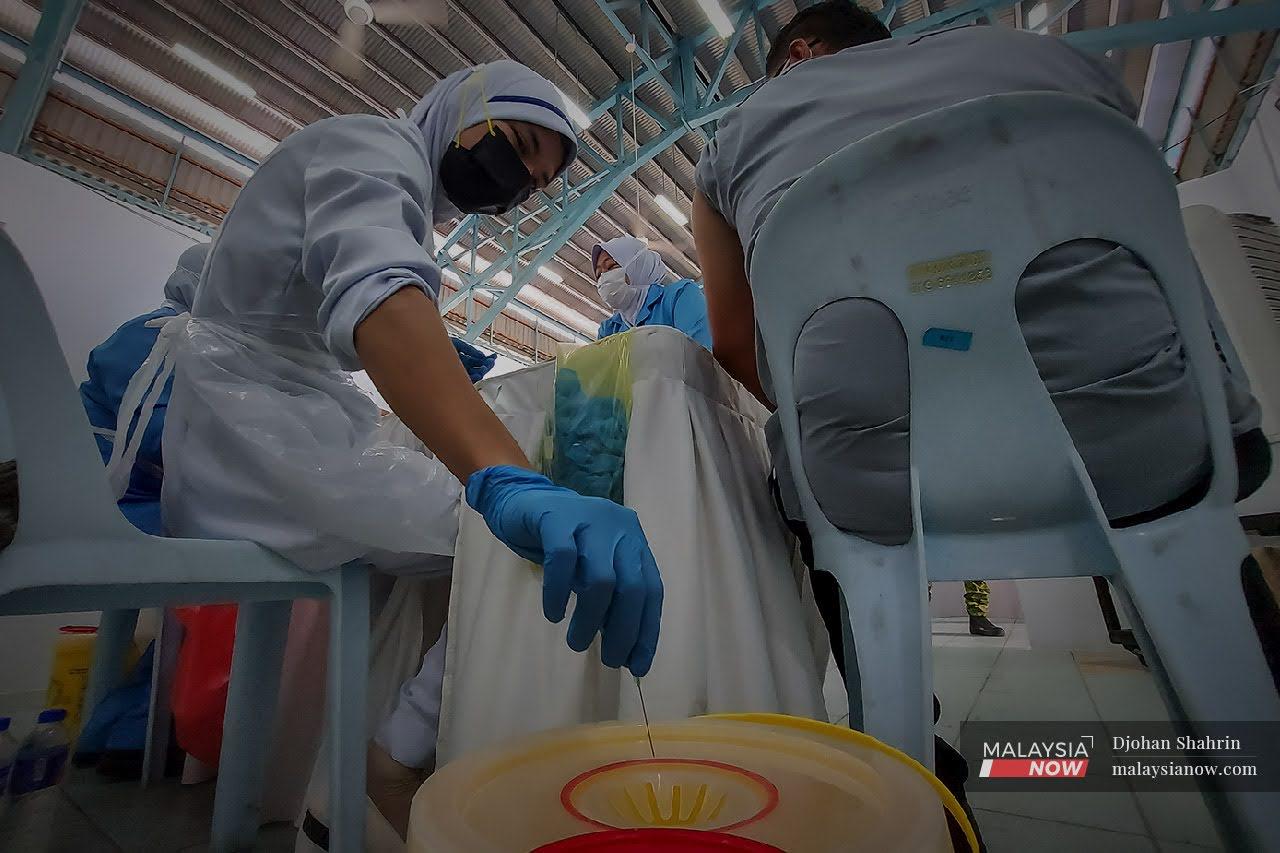 Petugas kesihatan dari Pusat Kesihatan Tangling membuang jarum suntikan ke dalam bekas khas di Pusat Pemberian Vaksin di Anjung Kelana, Taman Desa.