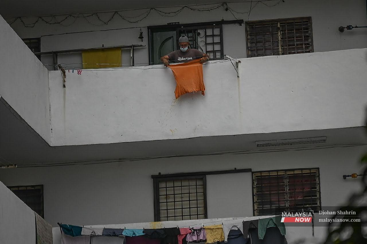 Seorang penduduk PPRT Pangsapuri Pantai Ria menjemur pakaian di hadapan balkoni rumahnya, kawasan ini dikenakan perintah kawalan pergerakan diperketatkan (PKPD) apabila beberapa penduduk di kawasan itu dikesan dijangkiti virus Covid19.