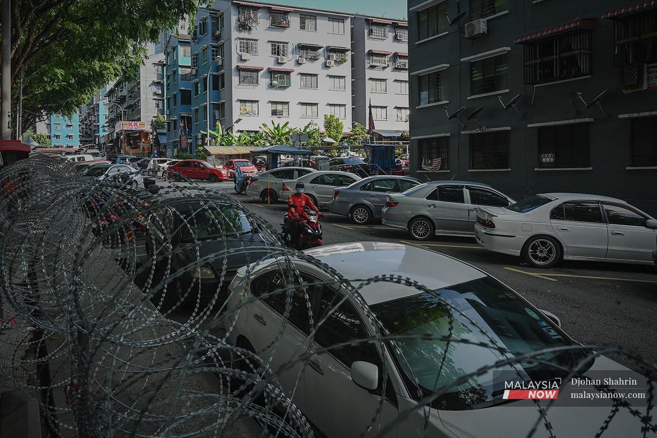 A motorcyclist rides past a barbed wire fence put up around the Taman Bukit Angkasa area in Kuala Lumpur which was placed under enhanced movement control order after a spike of Covid-19 cases.