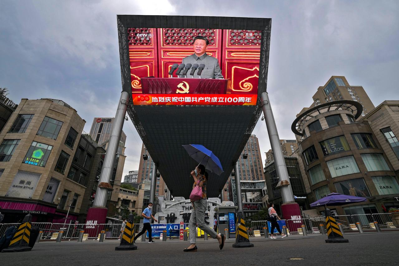People walk past a large video screen outside a shopping mall showing Chinese President Xi Jinping speaking during an event to commemorate the 100th anniversary of China's Communist Party at Tiananmen Square in Beijing, July 1. Photo: AP