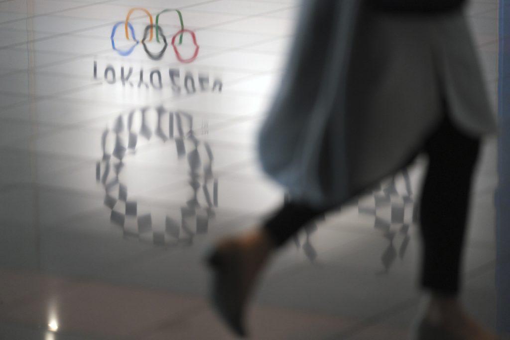 A woman walks near a reflection of Tokyo 2020 logo on the floor in Haneda Airport in Tokyo, June 14. Photo: AP