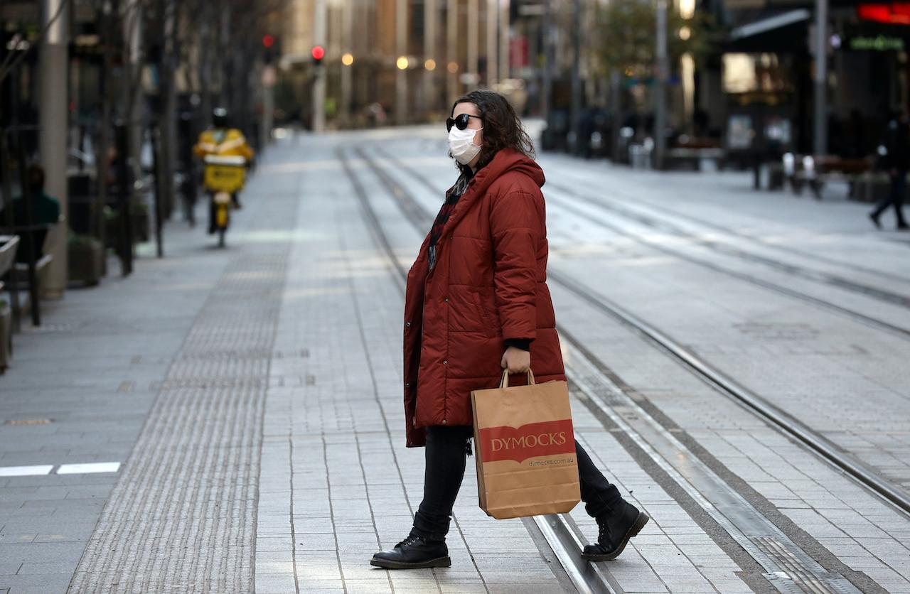 A woman crosses a normally busy street in Sydney, Wednesday, July 7. The outbreak has nearly reached 400 cases, and is spreading quickly across the largely unvaccinated city. Photo: AP