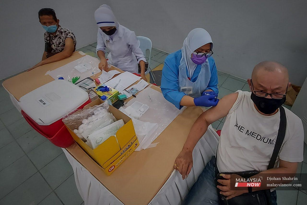 Petugas kesihatan dari Pusat Kesihatan Tangling memberikan suntikan vaksin dos ke dua  kepada penghuni Pusat Transit Gelendangan Kuala Lumpur di Anjung Kelana, Taman Desa.